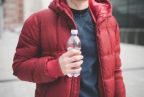 Cropped shot of young man drinking water outside city office — Stock Photo