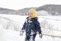 Toddler boy playing in snowy countryside field — Stock Photo