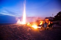 People on beach with bonfire and fireworks at night — Stock Photo