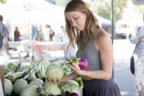 Frau am Obst- und Gemüsestand wählt rote Zwiebeln — Stockfoto