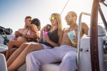 Les jeunes sur le yacht avec des boissons, riant — Photo de stock