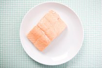 Assiette avec filet de saumon sur nappe à carreaux — Photo de stock