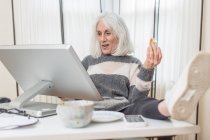 Portrait d'une femme âgée à la maison travaillant à son ordinateur de bureau à domicile — Photo de stock