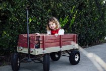Portrait of female toddler sitting in garden cart — Stock Photo