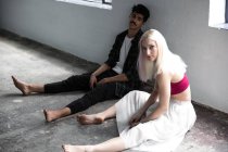 Bailarines tomando un descanso y sentados en el suelo en el estudio - foto de stock