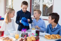 Boy with siblings unwrapping birthday gifts on patio — Stock Photo