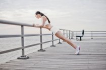 Femme faisant push ups sur quai en bois — Photo de stock
