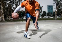 Молодой человек играет в баскетбол на площадке, крупным планом — стоковое фото
