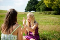 Young women playing patacake in a field — Stock Photo