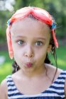 Portrait of girl in swimming goggles puckering lips in garden — Stock Photo