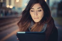 Mitte erwachsene Frau mit digitalem Tablet-Touchscreen am Bahnsteig in der Abenddämmerung — Stockfoto