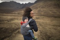 Madre llevando hijo en honda, Piscinas de hadas, cerca de Glenbrittle, Isla de Skye, Hébridas, Escocia - foto de stock