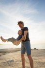 Mature man swinging his toddler daughter on beach, Calvi, Corsica, France — Stock Photo