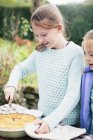 Girl cutting homemade pie in countryside garden — Stock Photo