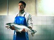 Fishmonger holding a salmon — Stock Photo