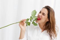 Senhora no meio de gobbling até uma rosa — Fotografia de Stock
