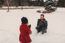 Chica lanzando bola de nieve a su padre - foto de stock