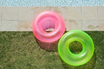Two inflatable rings by swimming pool in sunlight — Stock Photo