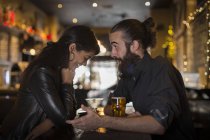 Young couple talking at table with cocktail and beer in public house — Stock Photo