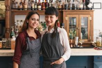 Portrait of two young female bartenders in cocktail bar — Stock Photo