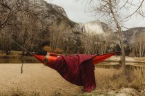 Жінка лежить у червоному гамаку, дивлячись на пейзаж, Національний парк Йосеміті, штат Каліфорнія, США. — стокове фото