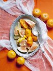 Нарезанные цитрусовые фрукты на тарелке ложкой — стоковое фото
