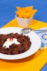 Plate of chili con carne with sour cream on table — Stock Photo