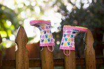 Rubber boots, upturned, on wooden fence posts — Stock Photo