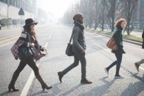 Cuatro adultos jóvenes cruzando la calle de la ciudad - foto de stock
