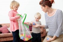 Madre e hijos jugando con bolas de plástico - foto de stock