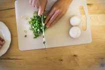 Young woman chopping spring onions, overhead view — Stock Photo
