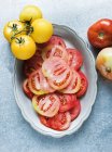Still life of red and yellow sliced tomatoes in dish — Stock Photo