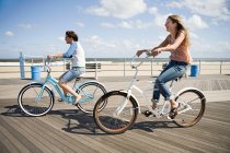 Две женщины катаются на велосипеде по набережной — стоковое фото
