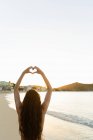 Rear view of woman making heart shape around sunlight — Stock Photo