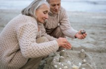 Coppia di anziani facendo un castello di sabbia — Foto stock