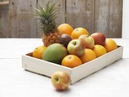 Вибір фруктів у коробці на побіленій дерев'яному столі — стокове фото