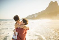 Молода пара обіймати на захід сонця, пляж Іпанема, Ріо, Бразилія — стокове фото