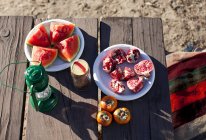 Cut fruit on plates on picnic table in sunlight — Stock Photo