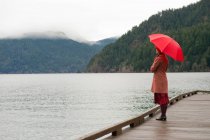 Mulher com guarda-chuva no cais de madeira — Fotografia de Stock