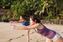 Women practicing yoga on a beach — Stock Photo