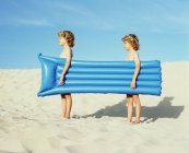 Twin boys carrying an inflatable — Stock Photo