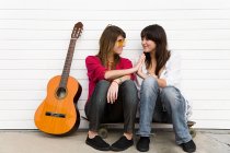 Две девушки сидят на полу с гитарой — стоковое фото