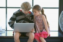 Девочка и мальчик за компьютером в доме — стоковое фото