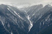 Vale e montanhas cobertas de neve cobertas de nevoeiro — Fotografia de Stock