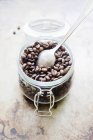 Банку кавових зерен з ложкою, підвищений вид — стокове фото