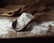 Cucharada de harina blanca en la mesa de madera - foto de stock