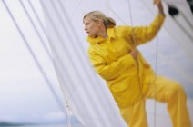 Жінка на човні в жовтих водонепроникних, тримає мотузку — стокове фото