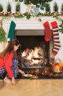 Girl placing festive items by fireplace — Stock Photo