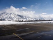 Estacionamiento vacío con montañas cubiertas de nieve - foto de stock