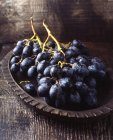Unch of black grapes in vintage wooden bowl — Stock Photo